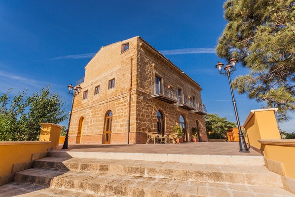 A stone building with a balcony and outdoor seating area.