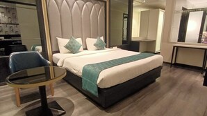 A modern hotel room with a large bed, a small round table, and a mirror. - Hotel Gopalas Residency (Bhiwandi)
