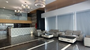 A modern lobby with a reception desk, leather sofas, a coffee table, and decorative lighting. - Hotel Gopalas Residency (Bhiwandi)