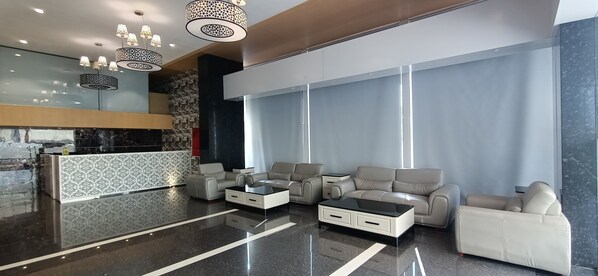 A modern lobby with a reception desk, leather sofas, a coffee table, and decorative lighting. - Hotel Gopalas Residency (Bhiwandi)