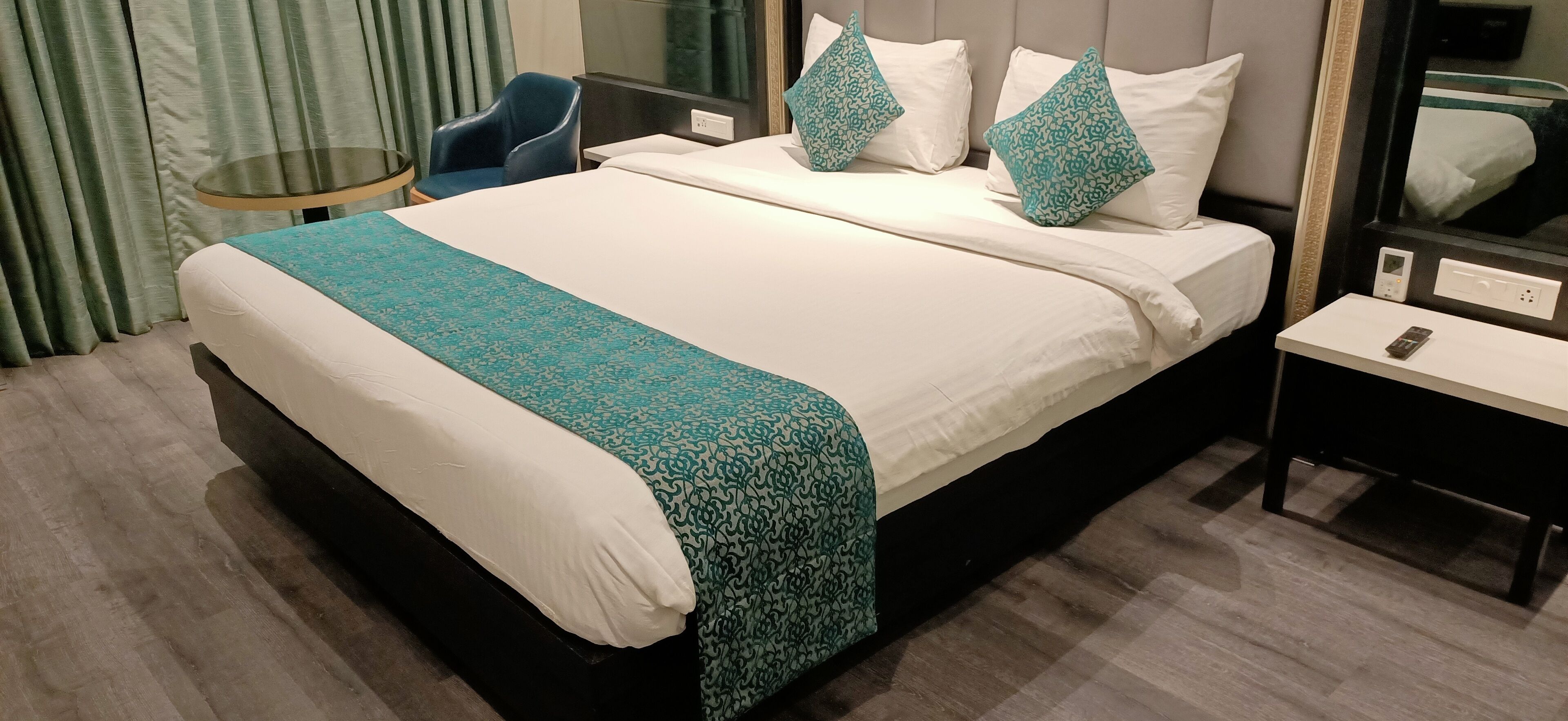 Une chambre d’hôtel avec un lit, une chaise, une table de chevet et un miroir.