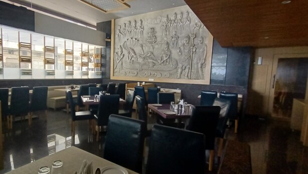 A restaurant with high tables and booths, a large decorative wall, and a modern interior design. - Hotel Gopalas Residency (Bhiwandi)