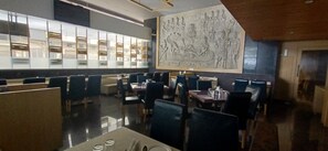 A restaurant with high tables and booths, a large decorative wall, and a modern interior design. - Hotel Gopalas Residency (Bhiwandi)