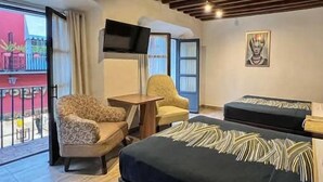 A hotel room with two beds, a TV, a chair, and a small table.