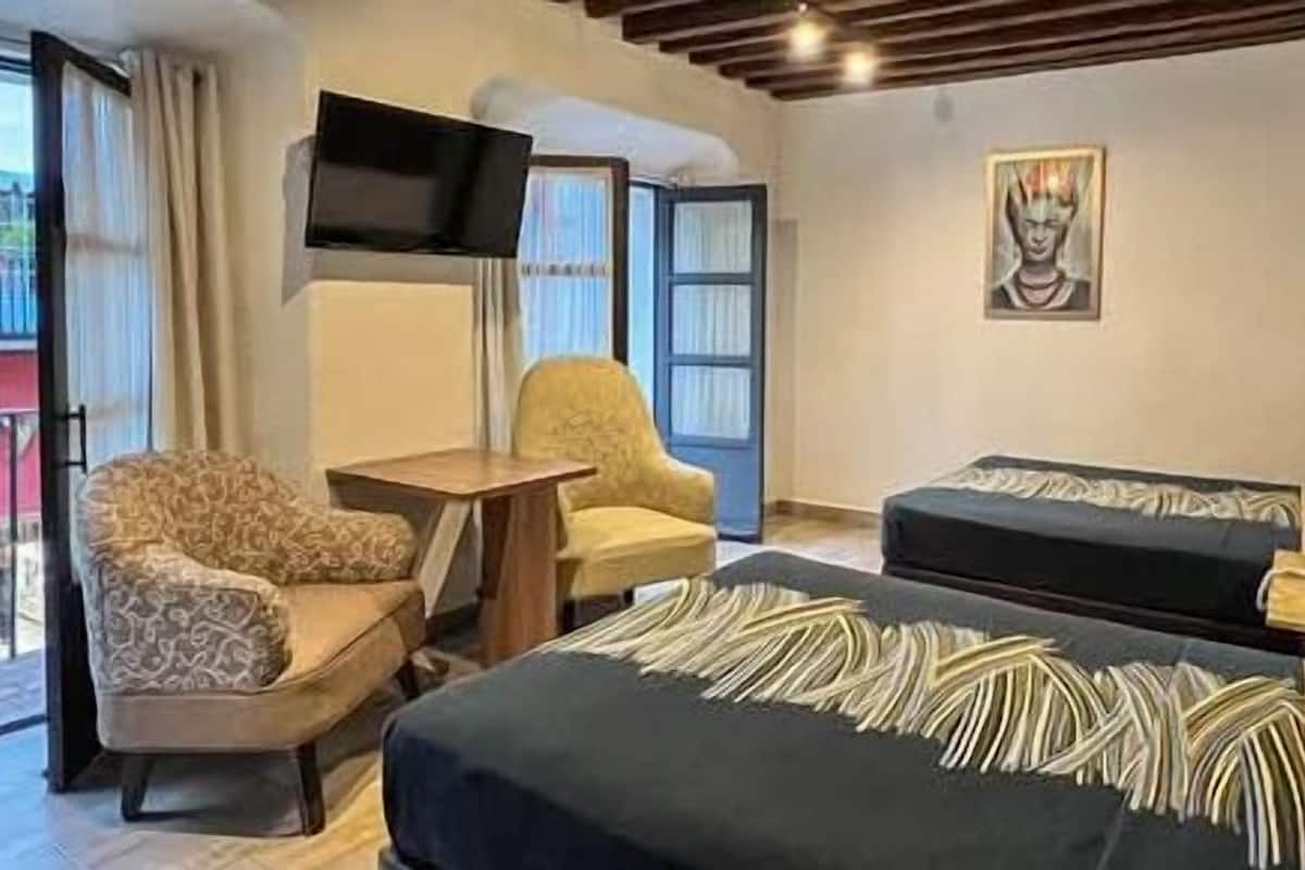 Una habitación de hotel con dos camas, televisión, una silla y una mesita.