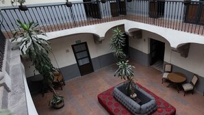 A courtyard with a red patterned sofa, potted plants, and a small table with chairs.