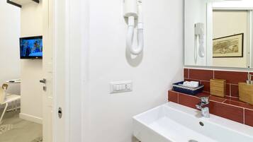 Ein Badezimmer mit einem weißen Waschbecken, einem Spiegel und einem an der Wand befestigten Föhn.