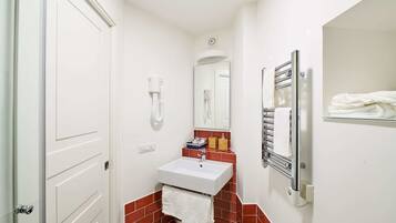 A small bathroom with a white sink, a mirror, and a towel rack.