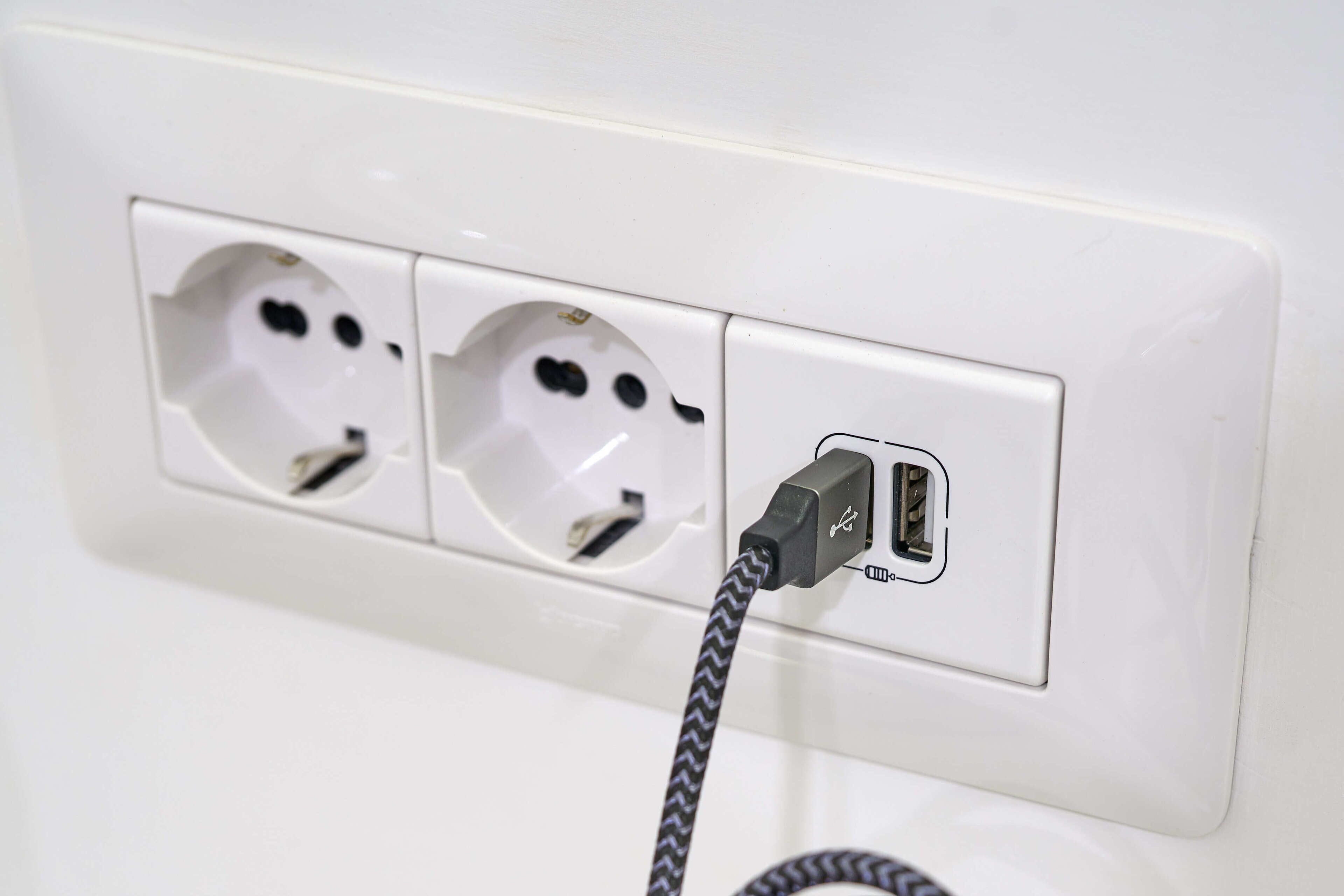 Une prise électrique blanche dotée de deux fiches et d’un port USB.