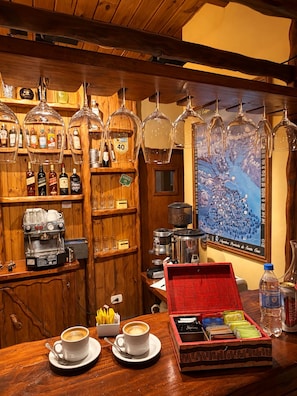 A bar area with wooden shelves, a coffee machine, and a red box of coffee pods. - Hosteria Rukahue (El Calafate)