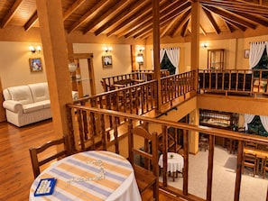 A hotel room with a wooden ceiling, a dining area with a table set for two, and a balcony with a railing. - Hosteria Rukahue (El Calafate)