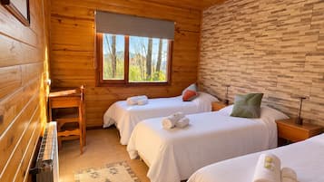 Habitación tipo cabaña con dos camas, ventana con vista a árboles y pared de madera.