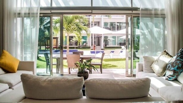 A modern hotel room with a large glass door leading to an outdoor pool area. - Via 38 Buda By Playa Paradise (Playa del Carmen)
