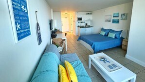 Un espace de vie compact comprenant un coin cuisine, un coin repas et une chambre avec un lit et un canapé.