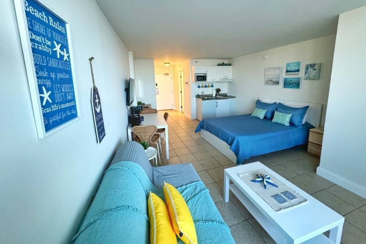 Een compacte woonruimte met een kitchenette, een eethoek en een slaapkamer met een bed en een slaapbank.