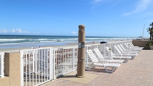 Une vue sur la plage, avec une rangée de chaises longues blanches et une clôture blanche.