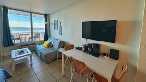 Une chambre avec un lit, un bureau, une télévision et une vue sur la plage.