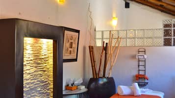 Relax in this serene space with a calming water feature, a comfortable bed, and a charming table setting.