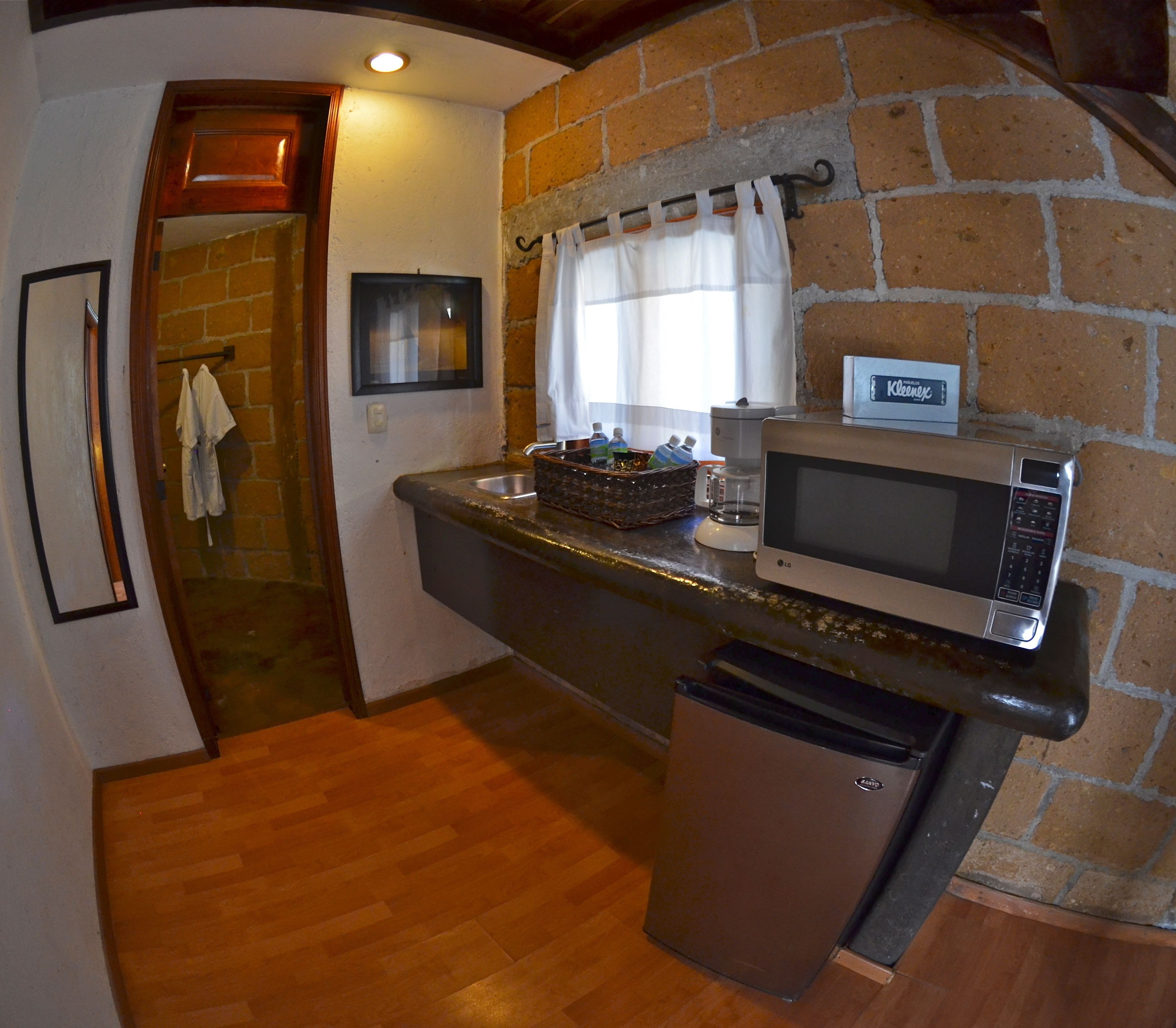 Una cocina compacta equipada con microondas, cafetera y refrigerador.