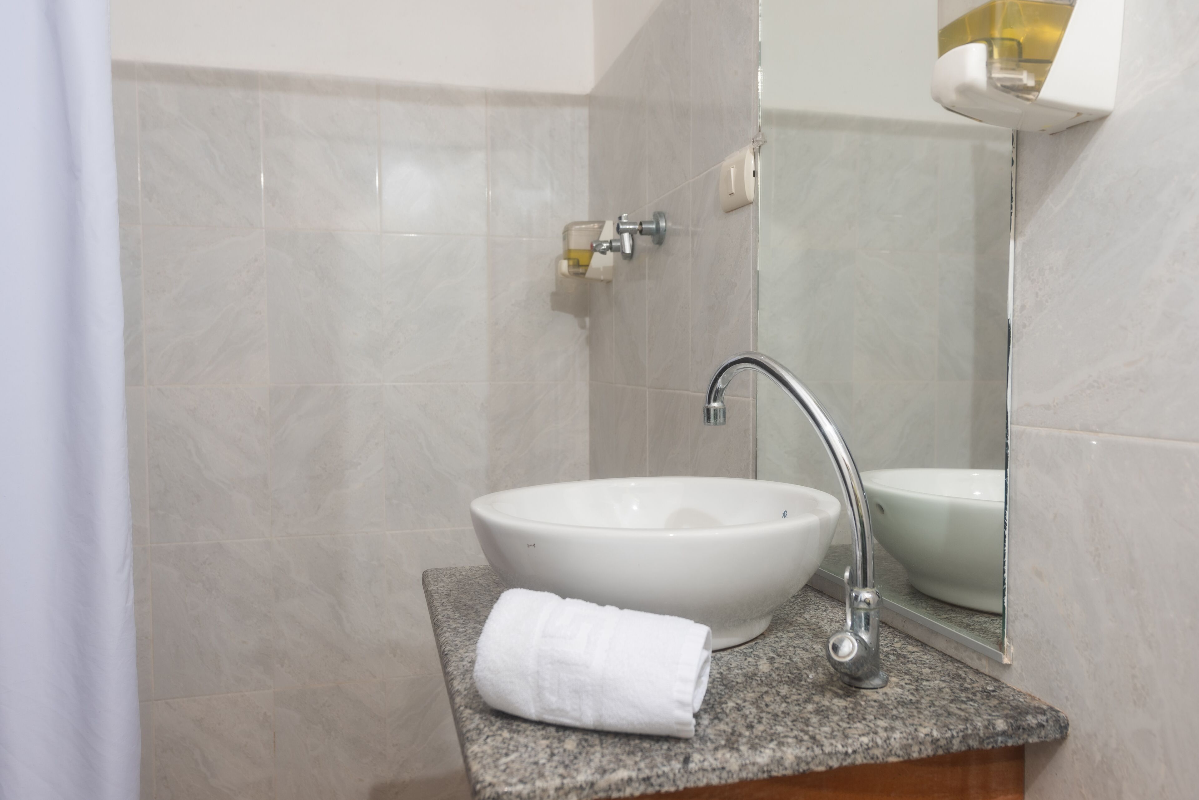 A bathroom with a white sink, a towel, and a mirror.