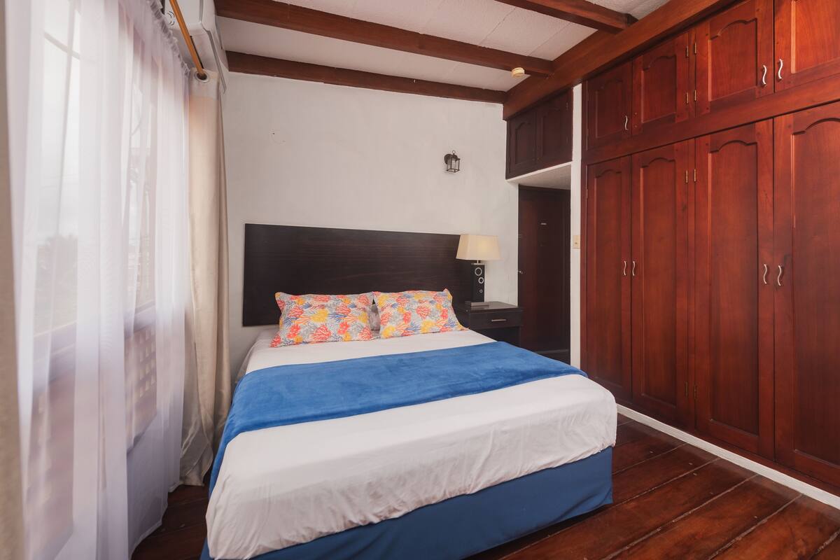 Ein Schlafzimmer mit einem Bett, einem Holzschrank und einem Nachttisch mit Lampe.
