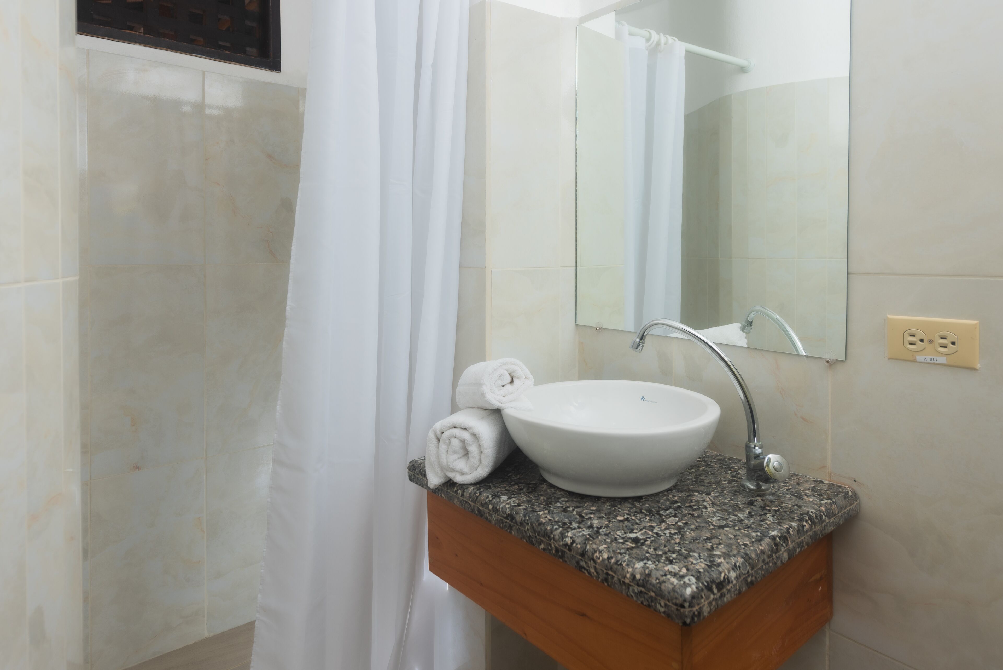 A bathroom with a white sink, a mirror, and a shower curtain.