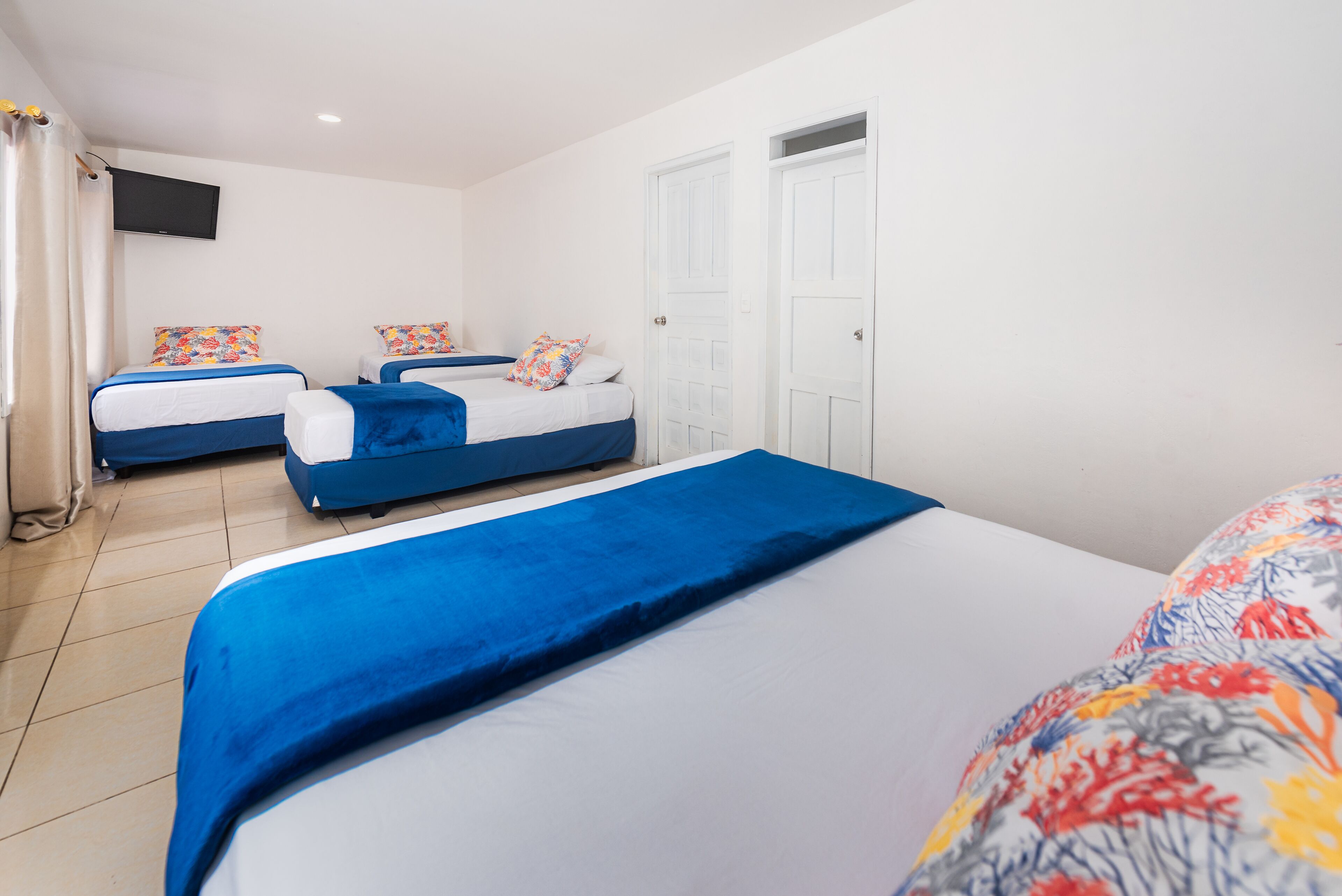 A hotel room with two beds, a large bed in the foreground and a smaller bed in the background.