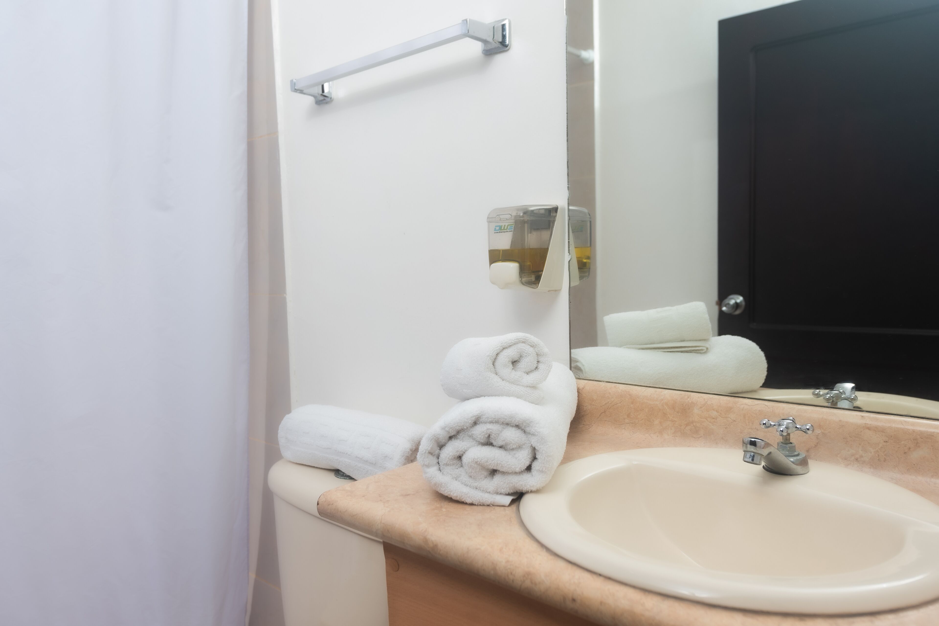 Une salle de bain équipée d’un lavabo, d’un distributeur de serviettes et d’un miroir.