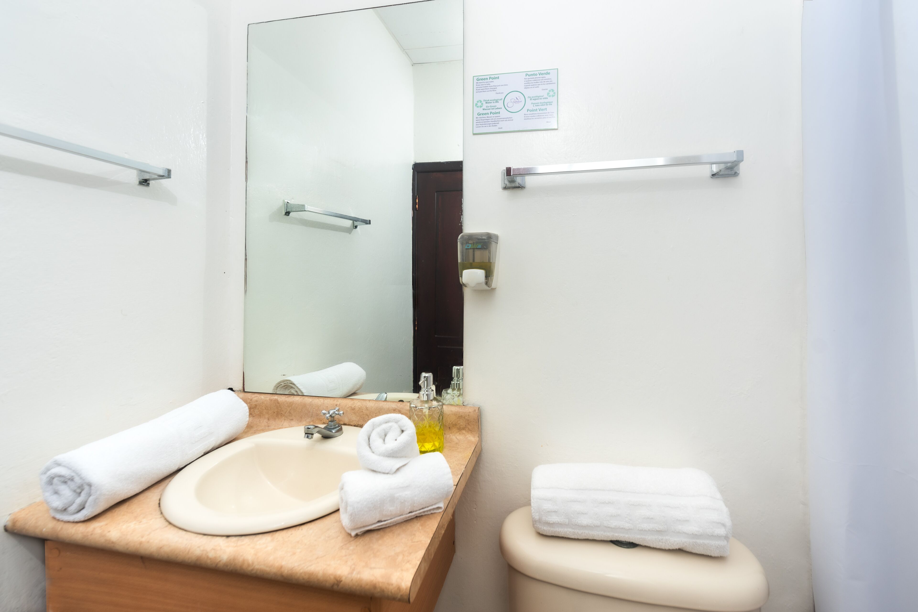 Een badkamer met een wastafel, spiegel, handdoekrek en toilet.