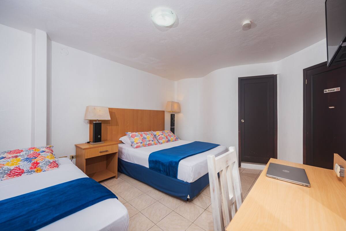 Ein Hotelzimmer mit zwei Betten, einem Schreibtisch und einem Laptop.