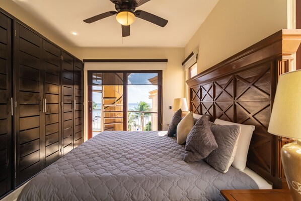 A bedroom with a large bed, dark wooden wardrobe, and a ceiling fan.