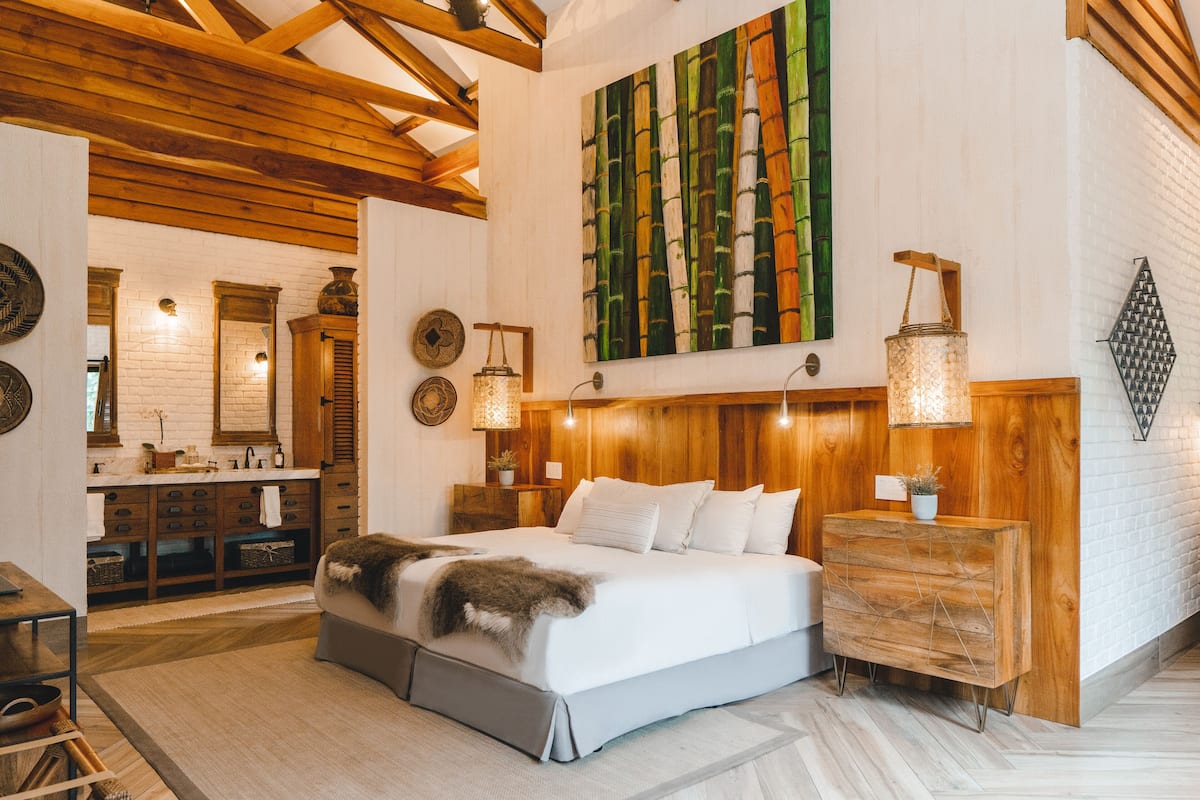 Un dormitorio con una cama grande, cabecera de madera, mesitas de noche y una lámpara fijada a la pared.