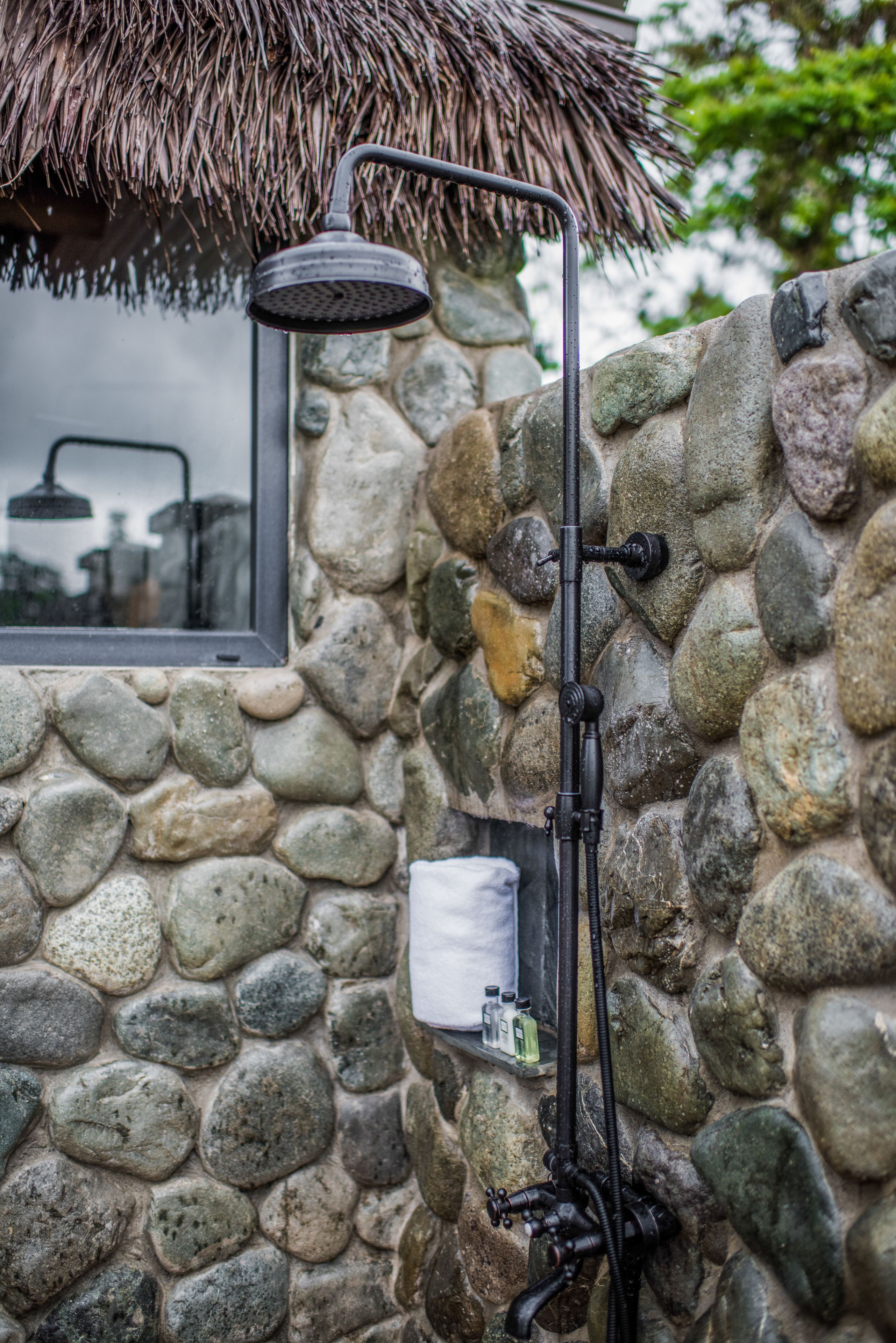 A stone wall with a showerhead and a window.