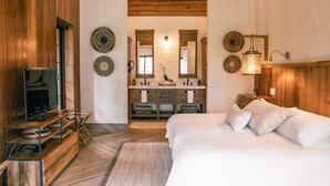 Un dormitorio con techo de madera, televisor, cama con almohadas, cómoda y espejo.