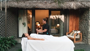 Sesión de masajes en un spa con pared de ladrillo, techo de paja y pared de piedra.