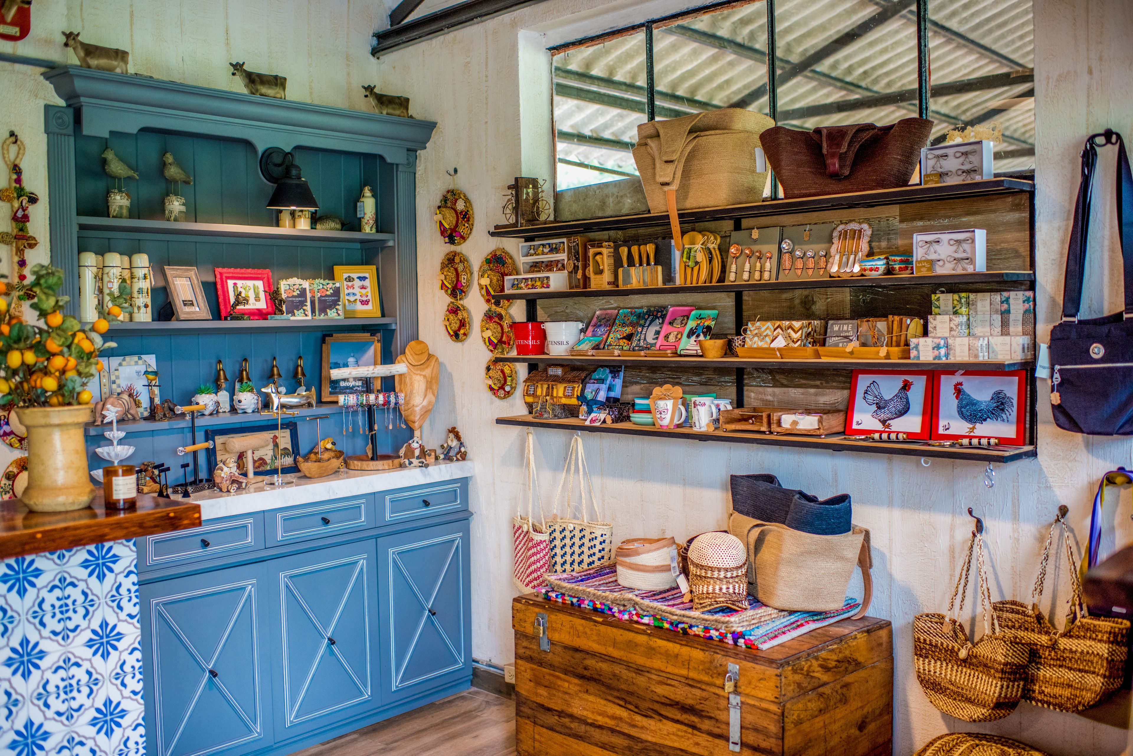 A room with a blue cabinet, wooden dresser, and shelves with various items including bags, hats, and framed pictures.
