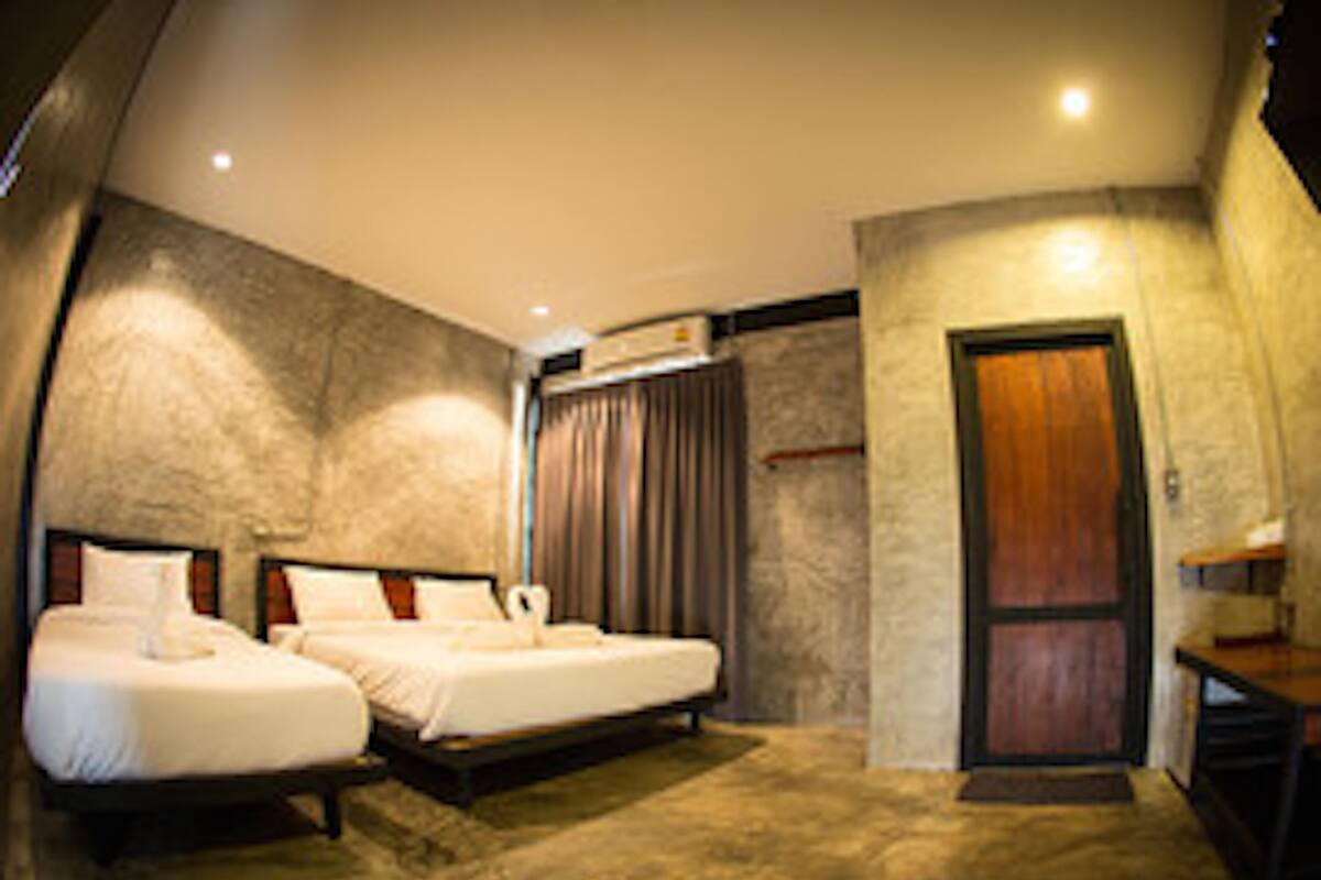 Een kamer met twee bedden, een houten deur en een stenen muur.