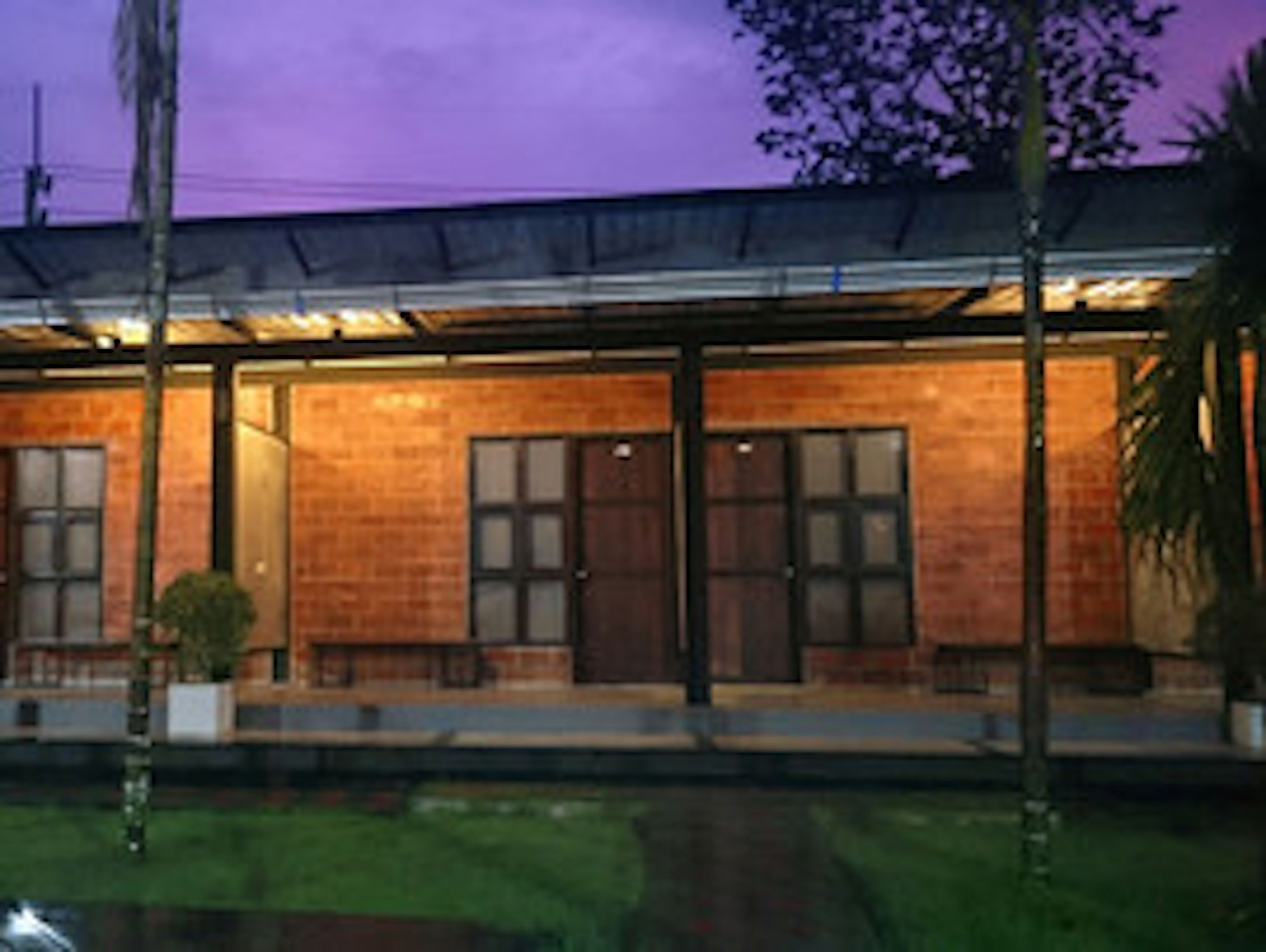 A modern building with a brick facade, large windows, and a covered porch area.