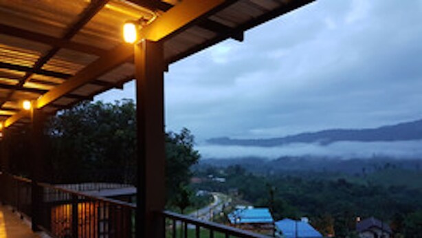 A covered balcony with a view of a valley and houses. - Sangkhlakiri Resort (Sangkhla Buri)