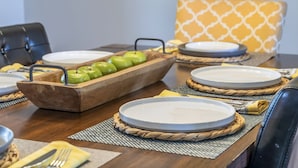 Une table à manger dressée avec des assiettes, un plateau en bois en forme de pomme et une chaise à motifs.