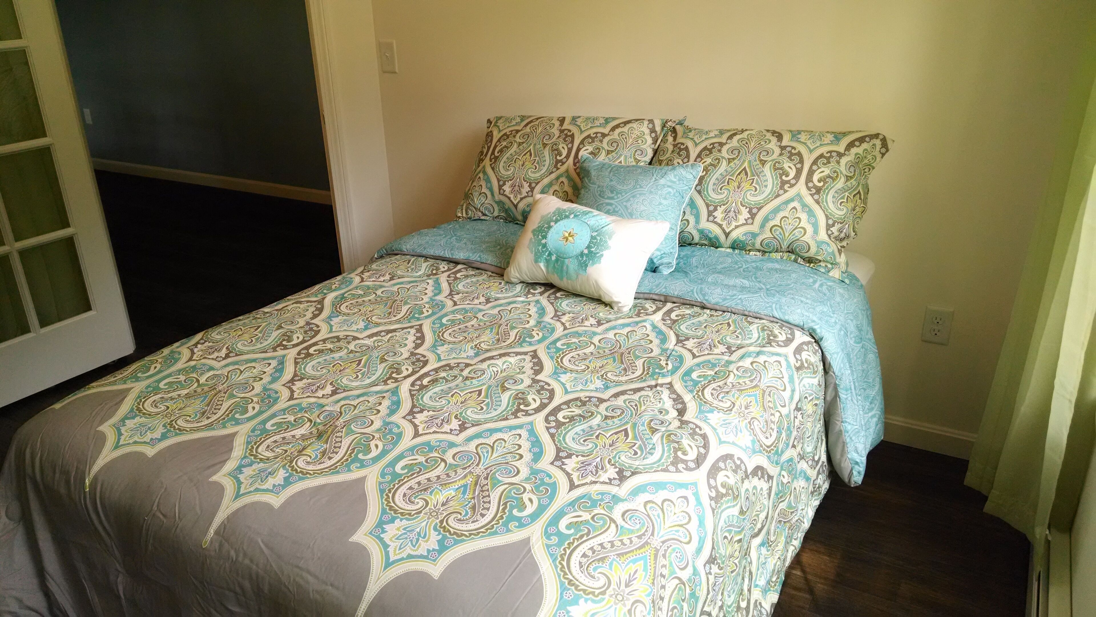 Een slaapkamer met een bed met behang, een raam met uitzicht en een deur naar buiten.