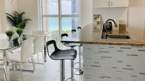 A modern kitchen with a large window, a granite countertop, and a stainless steel sink.