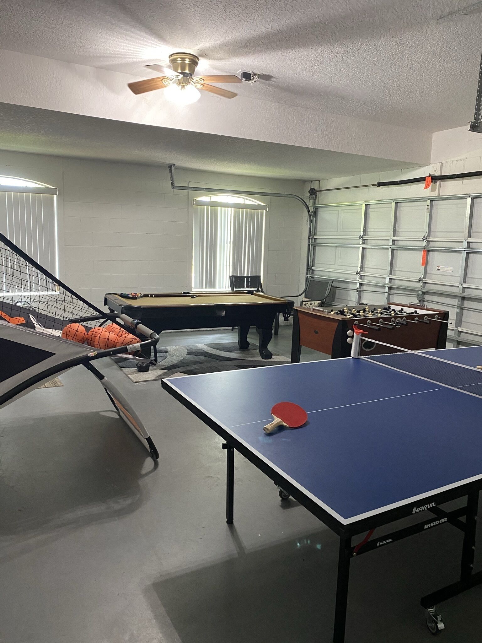 Une pièce équipée d’une table de ping-pong, d’une table de billard et d’un baby-foot.