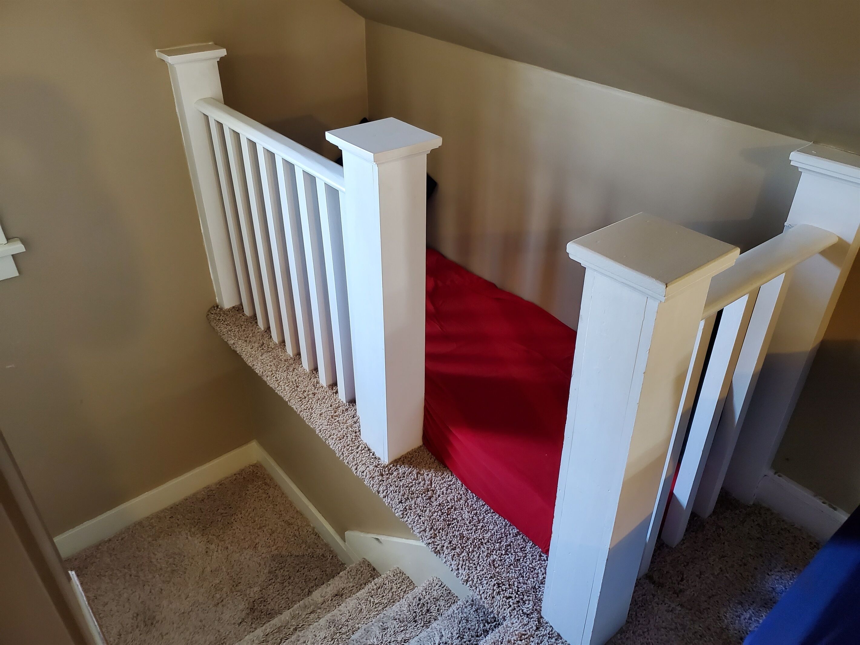 A staircase with white railings and a red carpet.