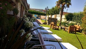 Un patio trasero con piscina, sillas de descanso y un muro de piedra.