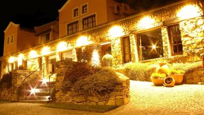 Un edificio con fachada de piedra, múltiples ventanas y una entrada bien iluminada.