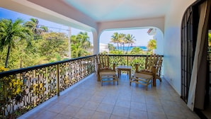 Een balkon met uitzicht op palmbomen en de oceaan.
