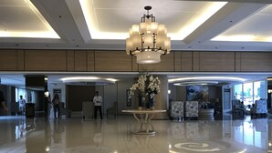 A spacious lobby with a central chandelier, a polished floor, and a reception desk. - Best Value 5-Star QCondo across Mall of Asia, near Airport, Casinos & Manila Bay (Pasay)