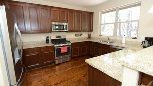 A kitchen with wooden cabinets, stainless steel appliances, granite countertops, and a window providing natural light.