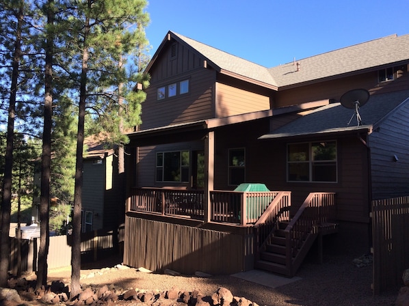 A two-story house with a deck, a satellite dish, and a staircase leading to the upper level.